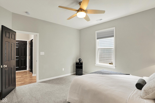 bedroom featuring light colored carpet, baseboards, and a ceiling fan