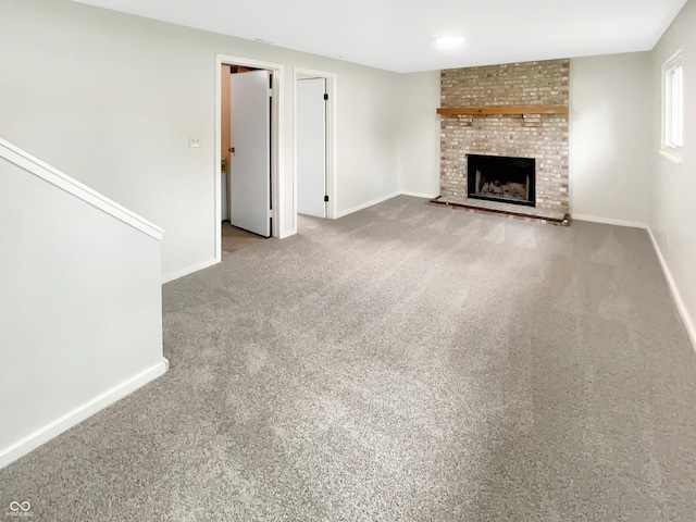 unfurnished living room featuring carpet, a fireplace, and baseboards