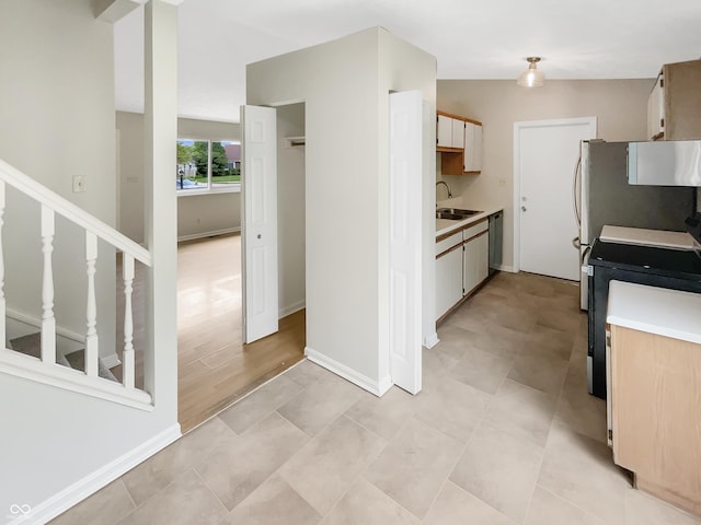 kitchen with a sink, stove, light countertops, and dishwashing machine