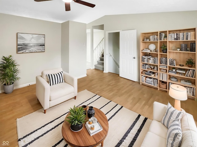 living room with light wood finished floors, ceiling fan, lofted ceiling, baseboards, and stairs