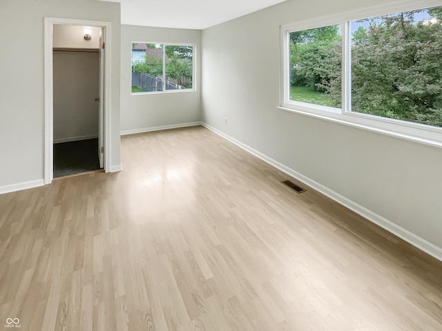 unfurnished bedroom with a spacious closet, wood finished floors, baseboards, and a closet