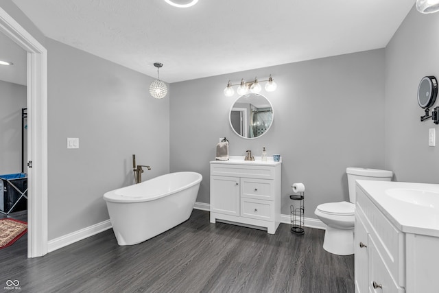 353 S Indiana St, Danville, IN 46122 - bathroom featuring two vanities, wood finished floors, a freestanding tub, and baseboards