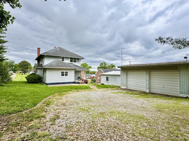 308 W Walnut St, Brownstown, IN 47220 - back of property with driveway, a garage, an outdoor structure, a chimney, and a yard