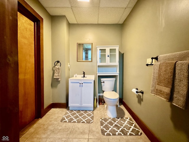 308 W Walnut St, Brownstown, IN 47220 - bathroom featuring toilet, vanity, a drop ceiling, baseboards, and tile patterned floors