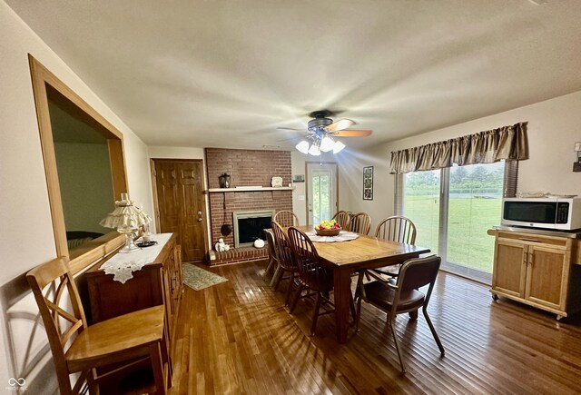 1154 W US Highway 136, Veedersburg, IN 47987 - dining area with dark wood-style flooring, a brick fireplace, and ceiling fan