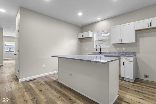 418 Harlan St, Indianapolis, IN 46201 - kitchen with white cabinets, recessed lighting, light stone counters, wood finished floors, and a center island