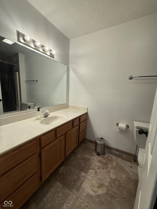 9535 Longwell Dr, Indianapolis, IN 46240 - bathroom featuring toilet, vanity, a textured ceiling, curtained shower, and stone finish floors