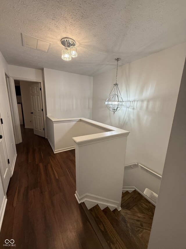 9535 Longwell Dr, Indianapolis, IN 46240 - corridor featuring an upstairs landing, a textured ceiling, dark wood-type flooring, a chandelier, and baseboards