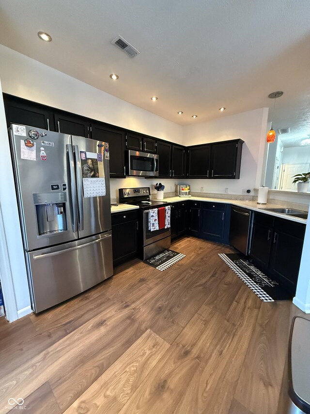 9535 Longwell Dr, Indianapolis, IN 46240 - kitchen with stainless steel appliances, dark cabinets, wood finished floors, light countertops, and a sink