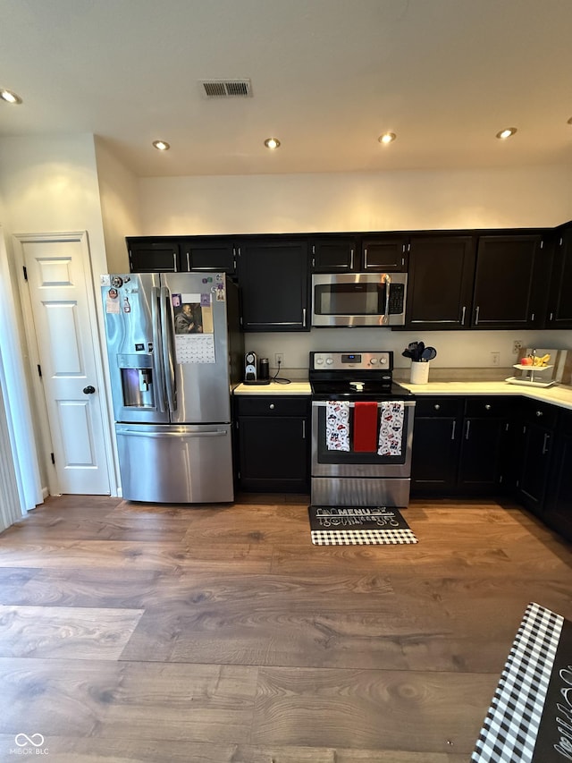 9535 Longwell Dr, Indianapolis, IN 46240 - kitchen featuring stainless steel appliances, dark cabinets, light wood finished floors, and recessed lighting