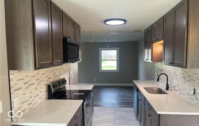 7731 Scarborough Blvd S, Indianapolis, IN 46256 - kitchen with stainless steel electric stove, a sink, backsplash, light countertops, and a textured ceiling