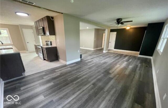 7731 Scarborough Blvd S, Indianapolis, IN 46256 - unfurnished living room with wood finished floors, baseboards, a ceiling fan, and a sink