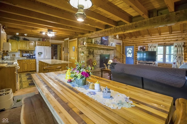 10484 N County Road 750 W, Freetown, IN 47235 - dining space with dark wood-type flooring, a stone fireplace, rustic walls, a ceiling fan, and wooden ceiling with exposed beams