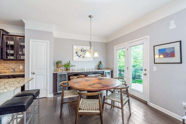2436 Gwinnett St, Carmel, IN 46032 - dining room with wine cooler, baseboards, dark wood-style floors, ornamental molding, and a chandelier