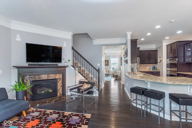 2436 Gwinnett St, Carmel, IN 46032 - living area featuring crown molding, stairs, a fireplace, dark wood-style floors, and recessed lighting