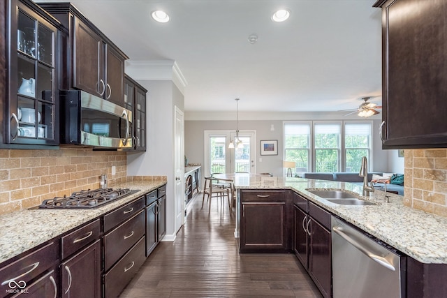 2436 Gwinnett St, Carmel, IN 46032 - kitchen with stainless steel appliances, a sink, dark brown cabinets, light stone counters, and ornamental molding