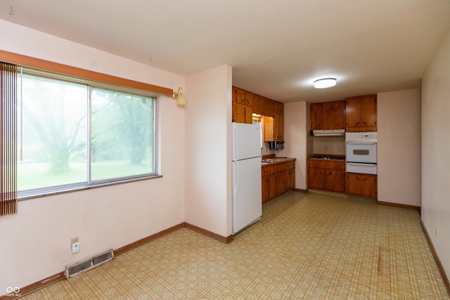 6498 N County Road 475 E, Pittsboro, IN 46167 - kitchen with white appliances, a warming drawer, brown cabinets, baseboards, and under cabinet range hood