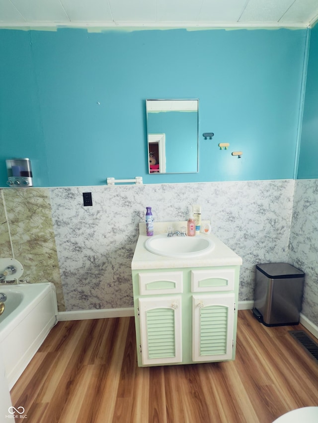 3385 W Commerce St, Vallonia, IN 47281 - bathroom with wood finished floors, vanity, a bathtub, baseboards, and a wainscoted wall