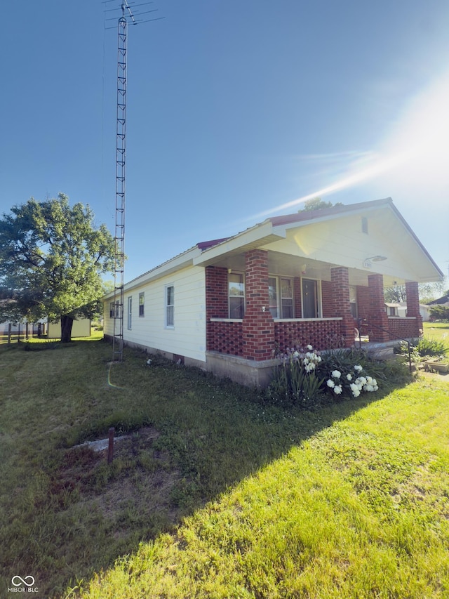 3385 W Commerce St, Vallonia, IN 47281 - view of home's exterior with a porch, a yard, and brick siding