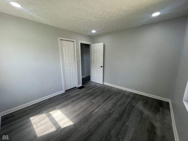 2911 E 35th St, Indianapolis, IN 46218 - unfurnished bedroom with dark wood-style floors, baseboards, a textured ceiling, recessed lighting, and a closet