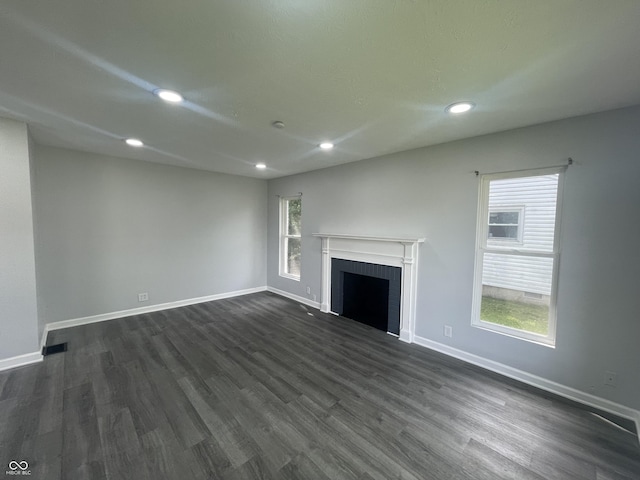 2911 E 35th St, Indianapolis, IN 46218 - unfurnished living room featuring dark wood-type flooring, baseboards, recessed lighting, and a brick fireplace