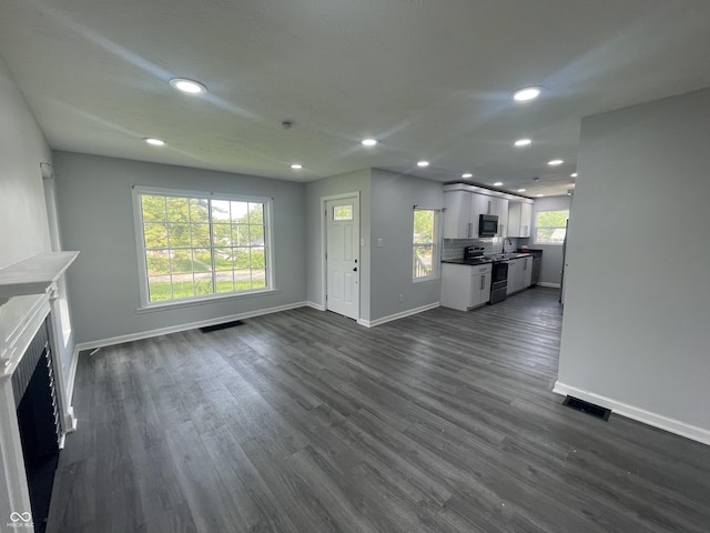 2911 E 35th St, Indianapolis, IN 46218 - unfurnished living room featuring baseboards, recessed lighting, dark wood finished floors, a sink, and a fireplace