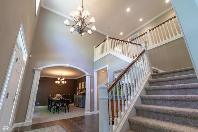 876 Box Turtle Ct, Columbus, IN 47201 - stairs with decorative columns, a chandelier, arched walkways, ornamental molding, and a towering ceiling