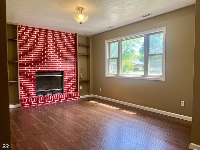 7824 Hearthstone Way, Indianapolis, IN 46227 - unfurnished living room featuring baseboards, wood finished floors, a brick fireplace, and a textured ceiling