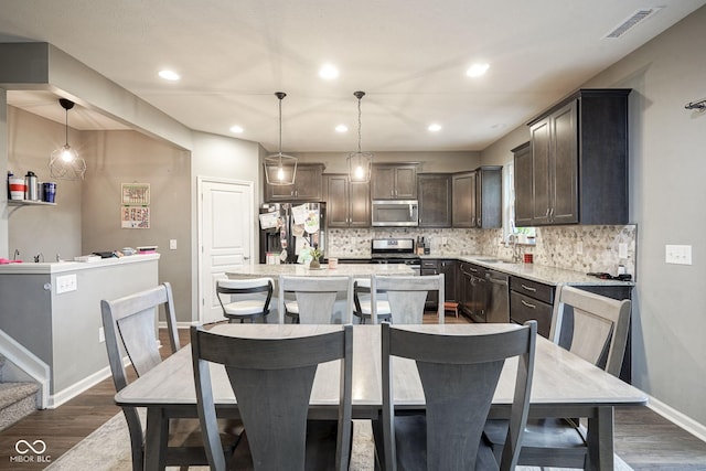 5374 John Quincy Adams Ct, Plainfield, IN 46168 - kitchen featuring appliances with stainless steel finishes, dark brown cabinets, dark wood-type flooring, backsplash, and a center island