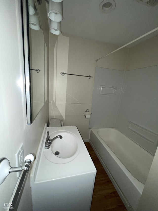 full bathroom featuring a sink, wood finished floors, and tub / shower combination