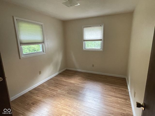 unfurnished room with plenty of natural light, light wood finished floors, and baseboards
