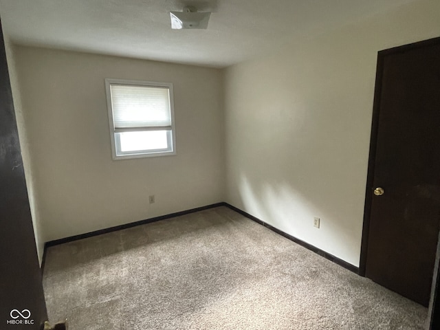 carpeted spare room featuring baseboards