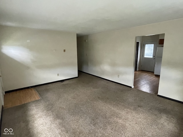 carpeted empty room with baseboards and wood finished floors