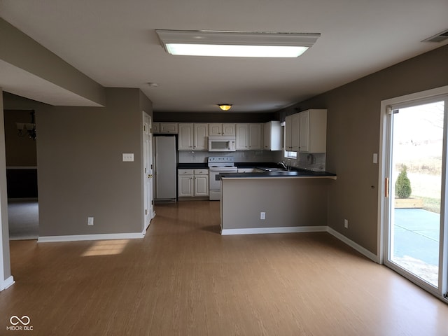 11754 Hamble Dr, Indianapolis, IN 46235 - kitchen with white appliances, light wood-style flooring, dark countertops, a peninsula, and white cabinets