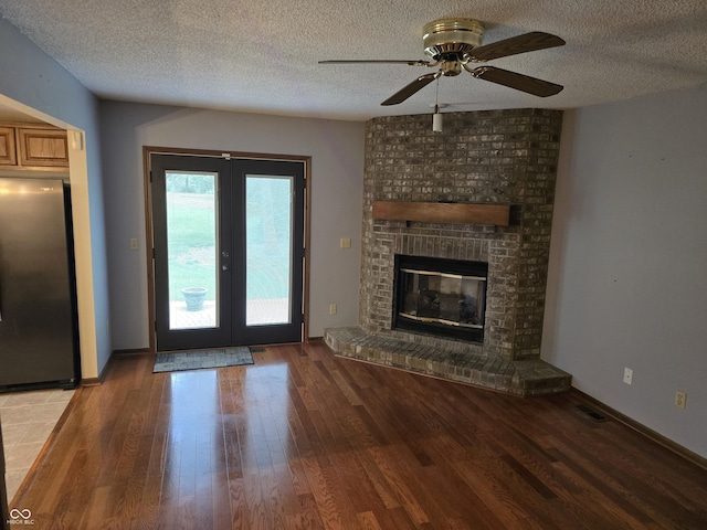 1805 River Run Trl, Fort Wayne, IN 46825 - unfurnished living room with wood finished floors, a textured ceiling, ceiling fan, a fireplace, and french doors