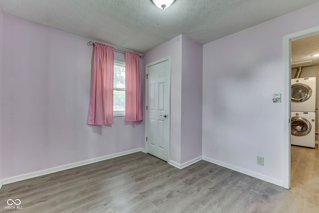 521 Elmhurst Pl, Whiteland, IN 46184 - empty room with wood finished floors, a textured ceiling, stacked washing machine and dryer, and baseboards