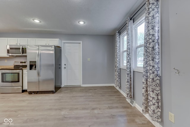 521 Elmhurst Pl, Whiteland, IN 46184 - kitchen featuring appliances with stainless steel finishes, baseboards, a textured ceiling, white cabinets, and light wood-type flooring