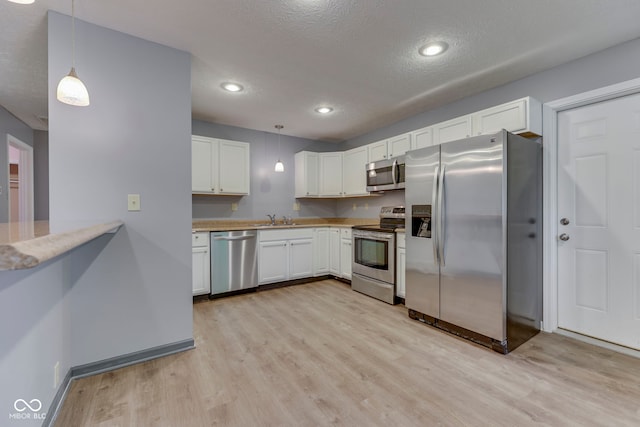 521 Elmhurst Pl, Whiteland, IN 46184 - kitchen with stainless steel appliances, a sink, light wood finished floors, white cabinetry, and a textured ceiling