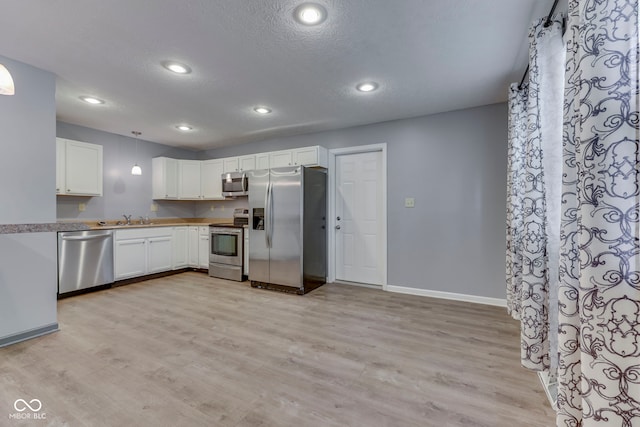 521 Elmhurst Pl, Whiteland, IN 46184 - kitchen with stainless steel appliances, light wood finished floors, white cabinets, a textured ceiling, and baseboards