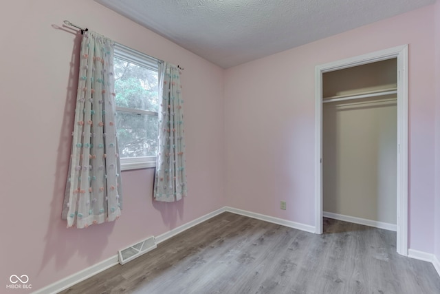521 Elmhurst Pl, Whiteland, IN 46184 - unfurnished bedroom with wood finished floors, a textured ceiling, baseboards, and a closet