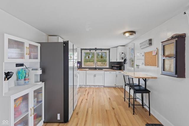 5594 S County Road 550 E, Greencastle, IN 46135 - kitchen with dishwasher, a sink, light wood-style flooring, white cabinets, and backsplash