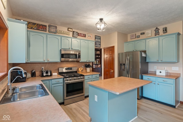 7978 Park Meadows Dr, Brownsburg, IN 46112 - kitchen featuring stainless steel appliances, a sink, light wood finished floors, light countertops, and a textured ceiling