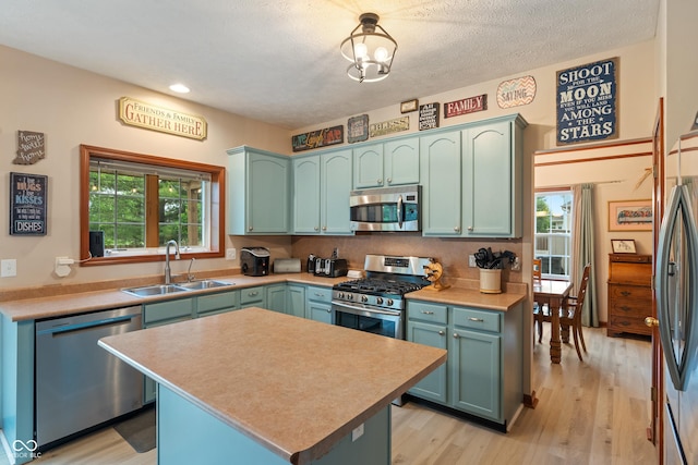 7978 Park Meadows Dr, Brownsburg, IN 46112 - kitchen featuring stainless steel appliances, a sink, light wood finished floors, light countertops, and a kitchen island