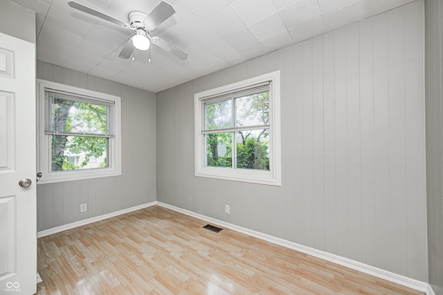 4621 E 17th St, Indianapolis, IN 46218 - empty room featuring light wood-style flooring, baseboards, a ceiling fan, and wooden walls