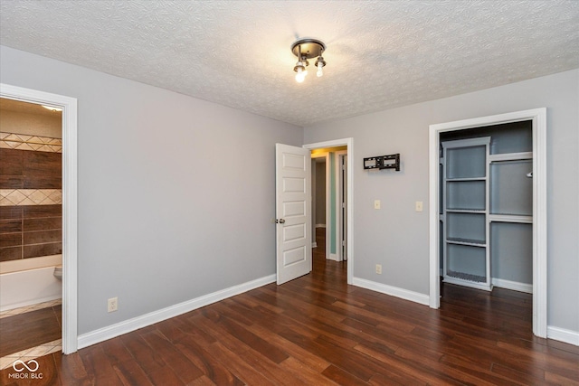 2519 N Boehning St, Indianapolis, IN 46219 - unfurnished bedroom featuring wood finished floors, a walk in closet, a textured ceiling, a closet, and baseboards
