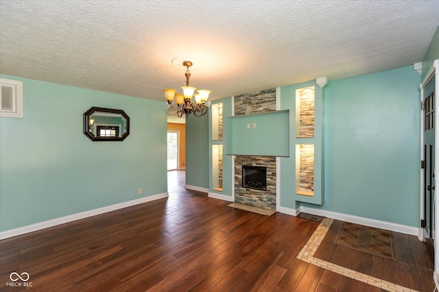 2519 N Boehning St, Indianapolis, IN 46219 - unfurnished living room with a chandelier, hardwood / wood-style flooring, baseboards, a fireplace, and a textured ceiling