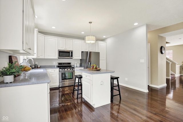 73 11th St NW, Carmel, IN 46032 - kitchen with stainless steel appliances, a kitchen breakfast bar, dark wood-type flooring, a sink, and white cabinetry