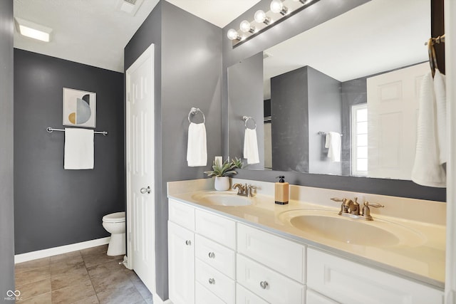 73 11th St NW, Carmel, IN 46032 - full bathroom featuring double vanity, toilet, baseboards, and tile patterned floors