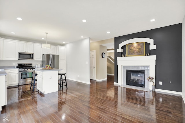 73 11th St NW, Carmel, IN 46032 - kitchen featuring appliances with stainless steel finishes, a breakfast bar, dark wood finished floors, a center island, and white cabinetry