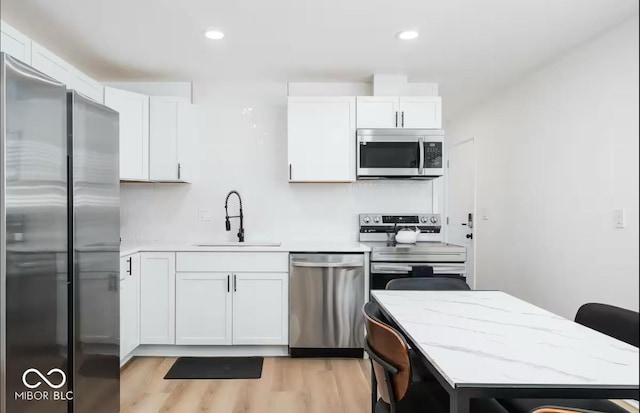 8744 Montery Ct, Indianapolis, IN 46226 - kitchen with stainless steel appliances, a sink, white cabinets, light wood-style flooring, and recessed lighting